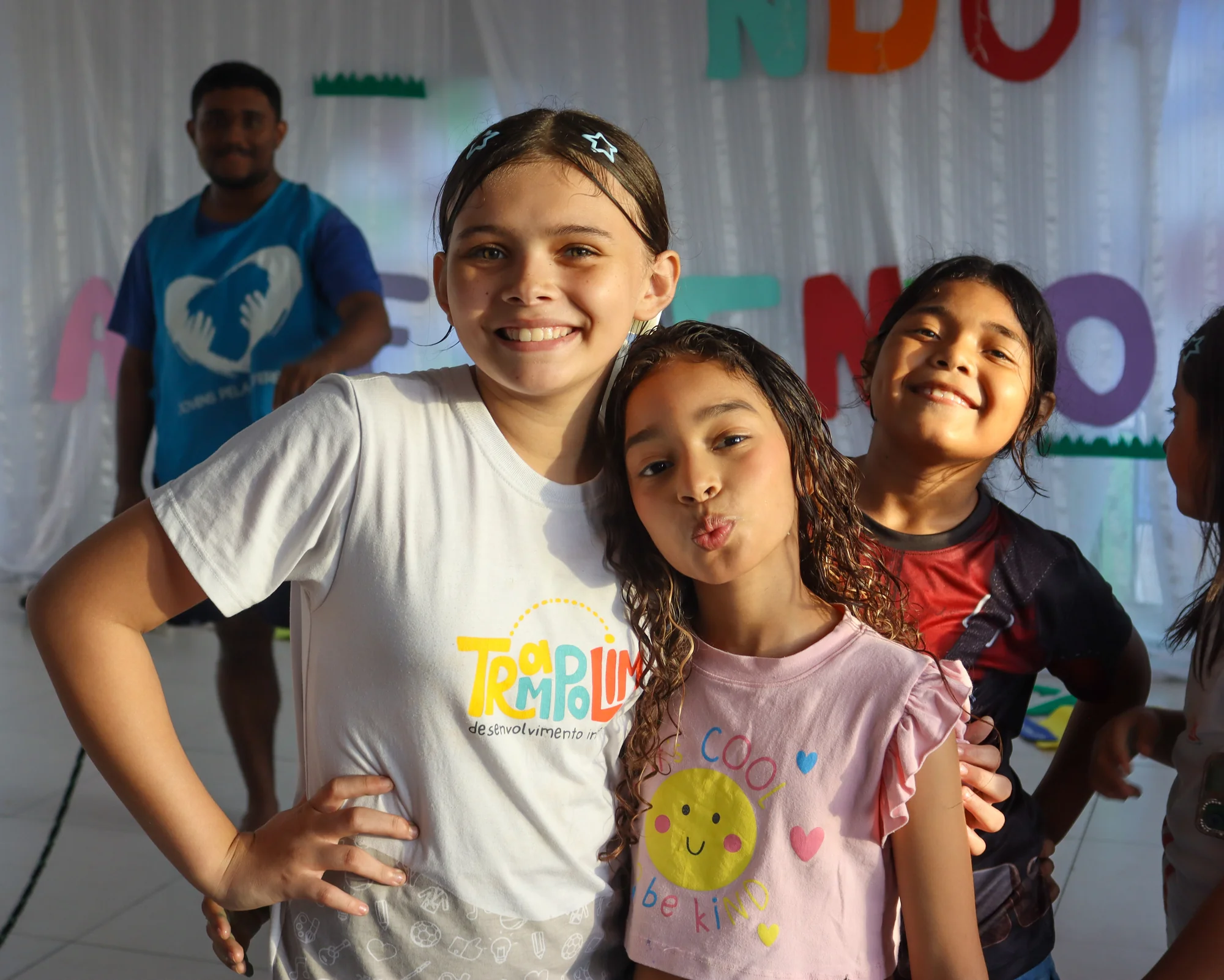 Três crianças posando juntas em um ambiente de festa