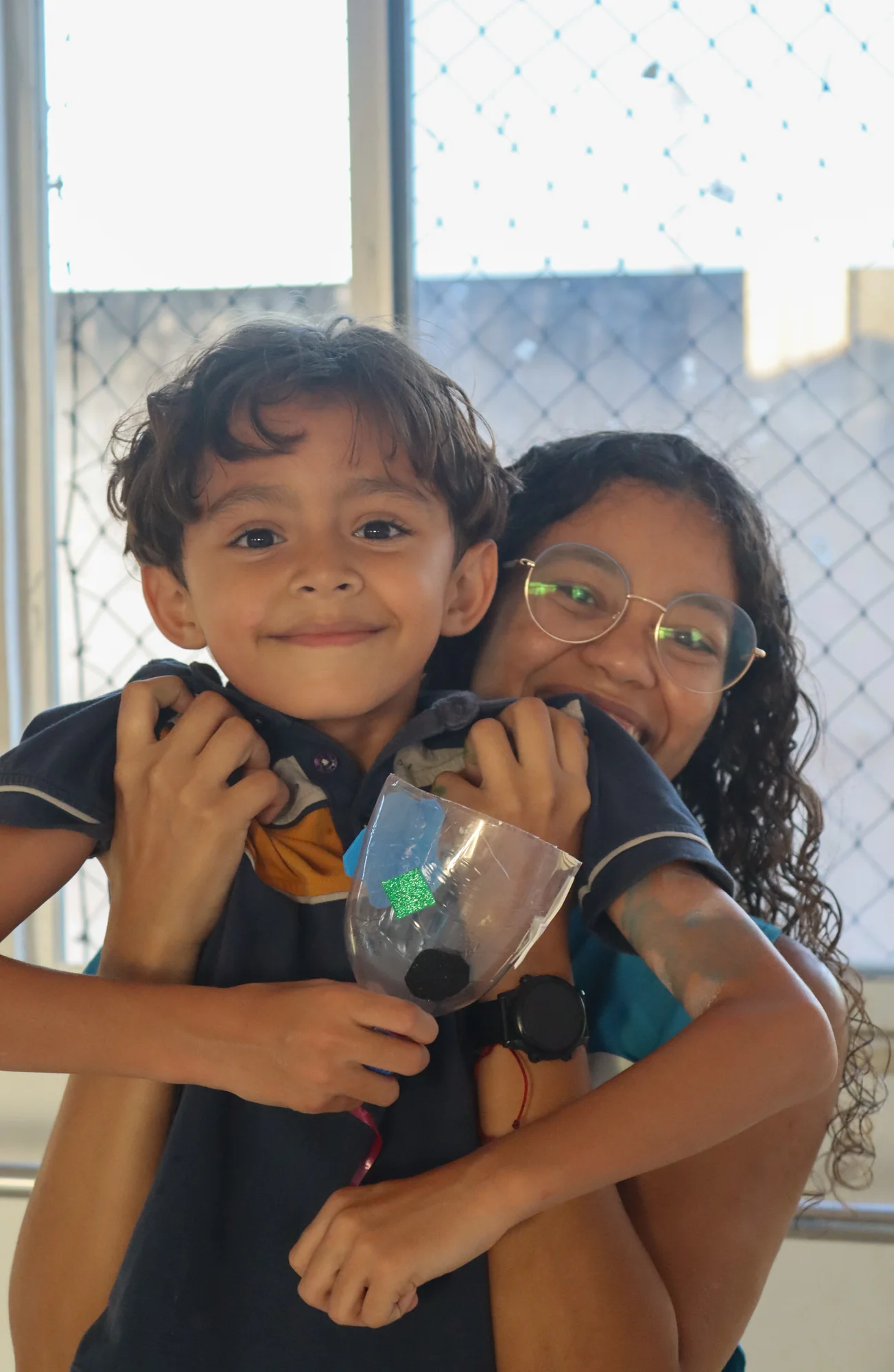 Duas crianças abraçadas perto de uma janela
