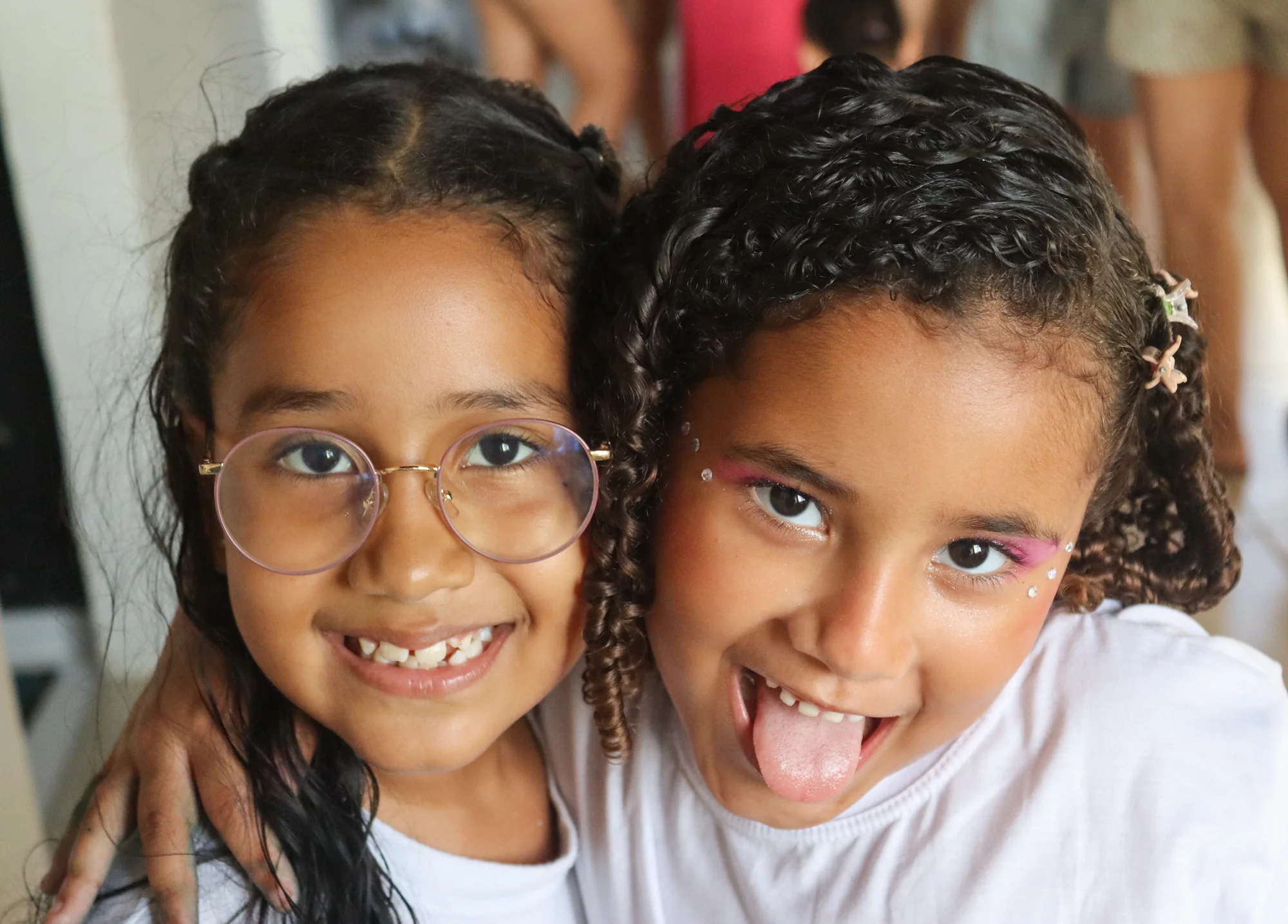 Duas crianças abraçadas, olhando para a câmera